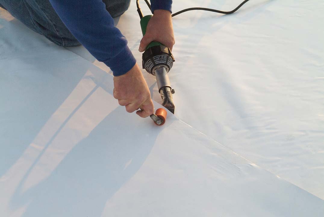 Ideal Roofing and Construction commercial roof seams, worker steaming flat commercial roof seams.